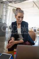 Thoughtful businesswoman looking down while sitting on chair