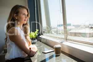 Side view of young businesswoman looking through window