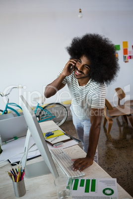 Smiling man with curly hair talking on phone in office