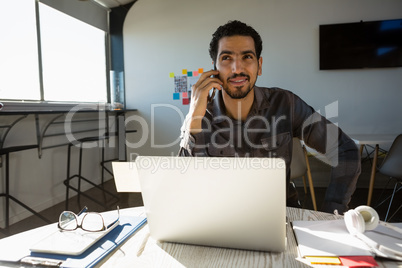 Man talking on phone while sitting at desk in office