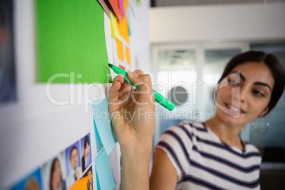 Young woman writing on sticky note at office