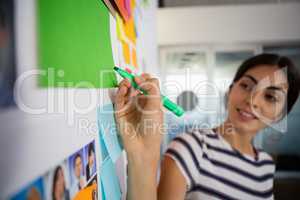 Young woman writing on sticky note at office