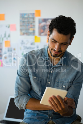 Young man using tablet against adhesive notes at office