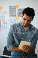 Young man using tablet against adhesive notes at office