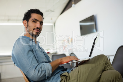 Portrait of young man using laptop in office