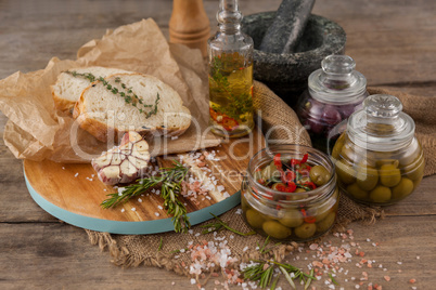 Olives in container with herbs and spices on table