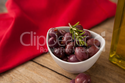 Olives with rosemary in bowl by napkin
