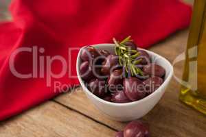 Olives with rosemary in bowl by napkin