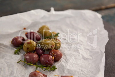 High angle view of olives with thyme on paper