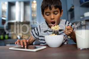 Close up of boy using tablet computer while having breakfast