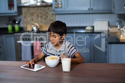 Boy using digitabl tablet while having breakfast