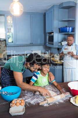 Father assisting son for rolling dough