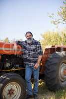 Portrait of confident man leaning on tractor