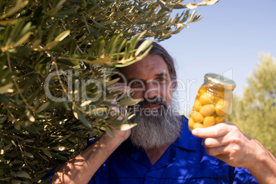 Man talking on mobile phone while examining pickled olive
