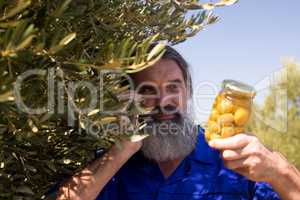 Man talking on mobile phone while examining pickled olive