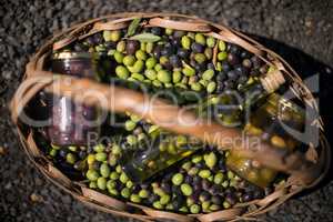 Close-up of olives, jar and olive oil bottle in basket