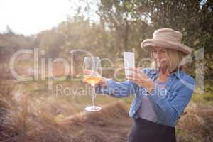 Woman taking a photo of wine glass in olives farm