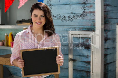 Smiling businesswoman holding writing slate while standing by food truck