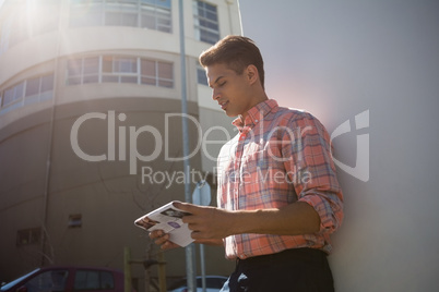 Man reading paper while standing by wall