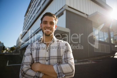 Smiling man with arms crossed standing by building in city