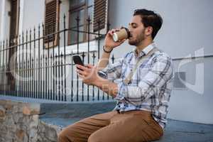 Man having drink while using mobile phone
