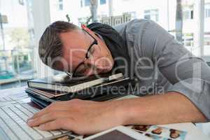 Tired businessman sleeping on files in studio