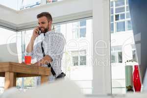 Low angle view businessman talking on mobile phone while standing at desk