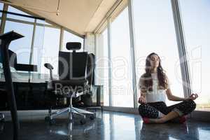 Young businesswoman doing yoga on floor