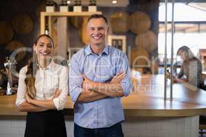 Couple standing with arms crossed near bar counter