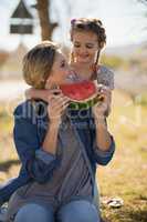 Mother and daughter having watermelon slice in park