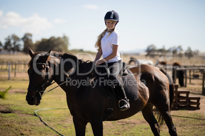 Smiling girl riding a horse in the ranch