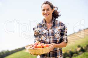 Portrait of smiling woman holding apple basket