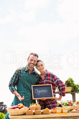 Portrait of young couple with blackboard selling organic vegetables