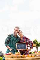 Portrait of young couple with blackboard selling organic vegetables