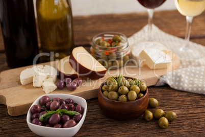 Close up of olives with cheeses and vegetable by wineglass