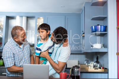 Happy father carrying son while standing with man