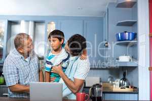 Happy father carrying son while standing with man