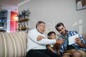 Smiling family using tablet while sitting on sofa