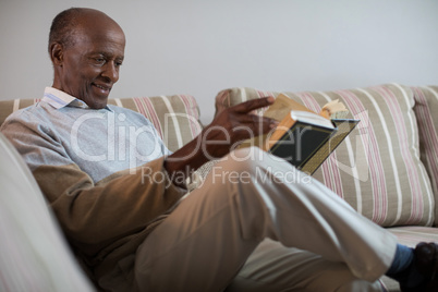 Smiling senior man reading book at home