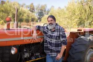 Portrait of confident man leaning on tractor
