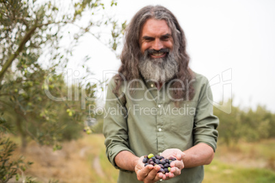 Happy man holding harvested olives in farm