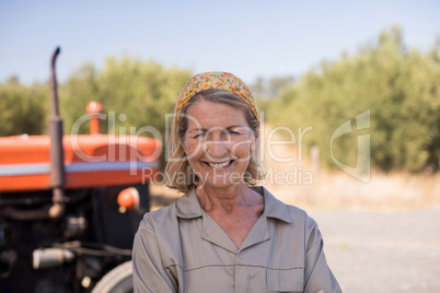 Portrait of happy woman standing against tractor in olive farm