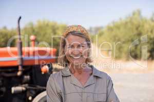 Portrait of happy woman standing against tractor in olive farm