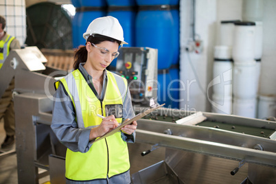 Female technician writing in clipboard