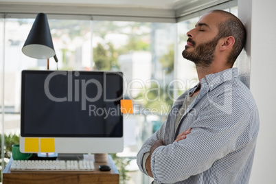 Designer relaxing while leaning on wall at office