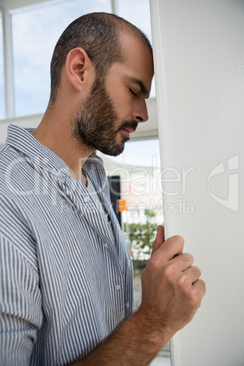 Frustrated designer with eyes closed leaning on wall