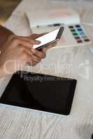 Cropped hands of man using phone at desk in office