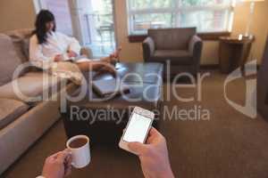 Man using mobile while having coffee in the living room