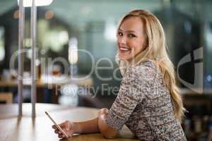 Smiling beautiful woman using mobile phone at bar counter