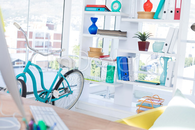 Computer on desk with bicycle and shelf